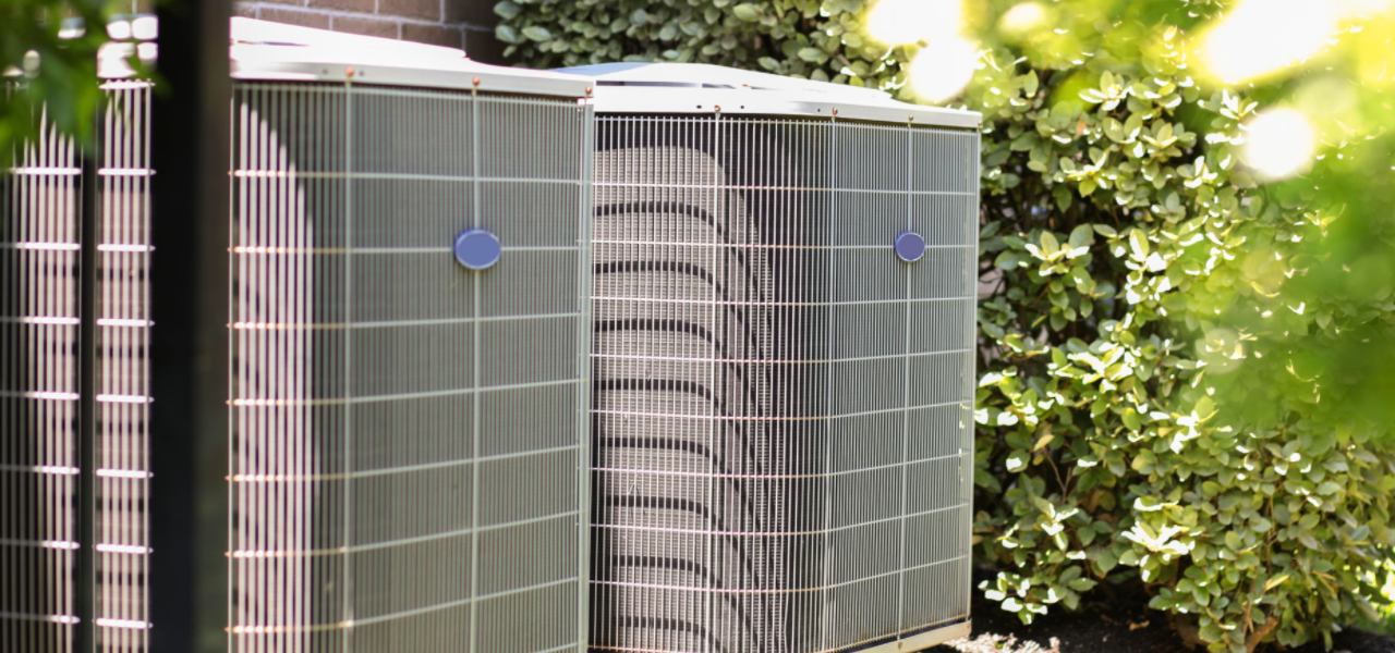 Two outdoor air conditioning units next to a home.