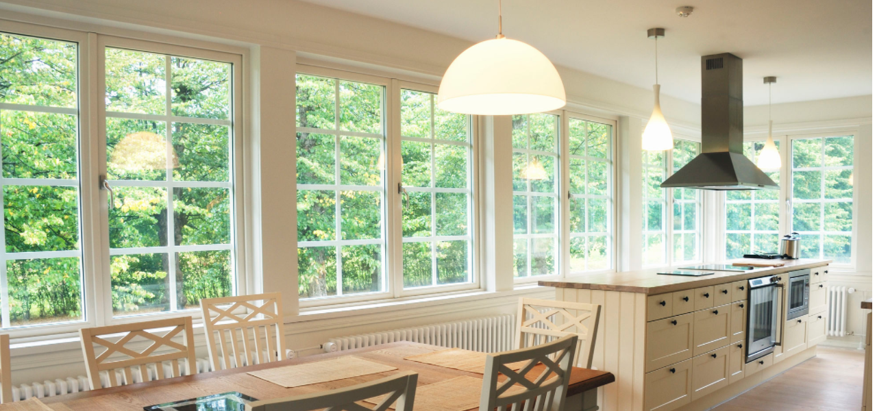 A modern, long kitchen that's well lit using primarily white birch inside.